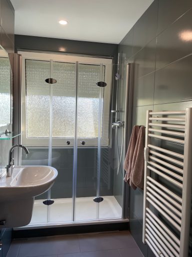 Badezimmer Modernes Bad mit Dusche, Waschbecken und Handtuchhalter. Helle, schlichte Gestaltung.